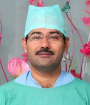 Male surgeon in green surgical scrubs and cap with floral background – operation theatre setting