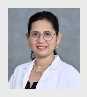 Smiling female doctor with glasses and white coat against grey background – healthcare portrait